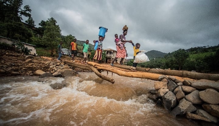 Affected families carry emergency-supplies over a makeshift-bridge-after-the mudslide in Freetown Sierra Leone