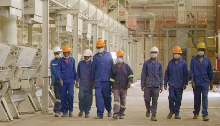 Group of people walking in hard hats and overalls at work