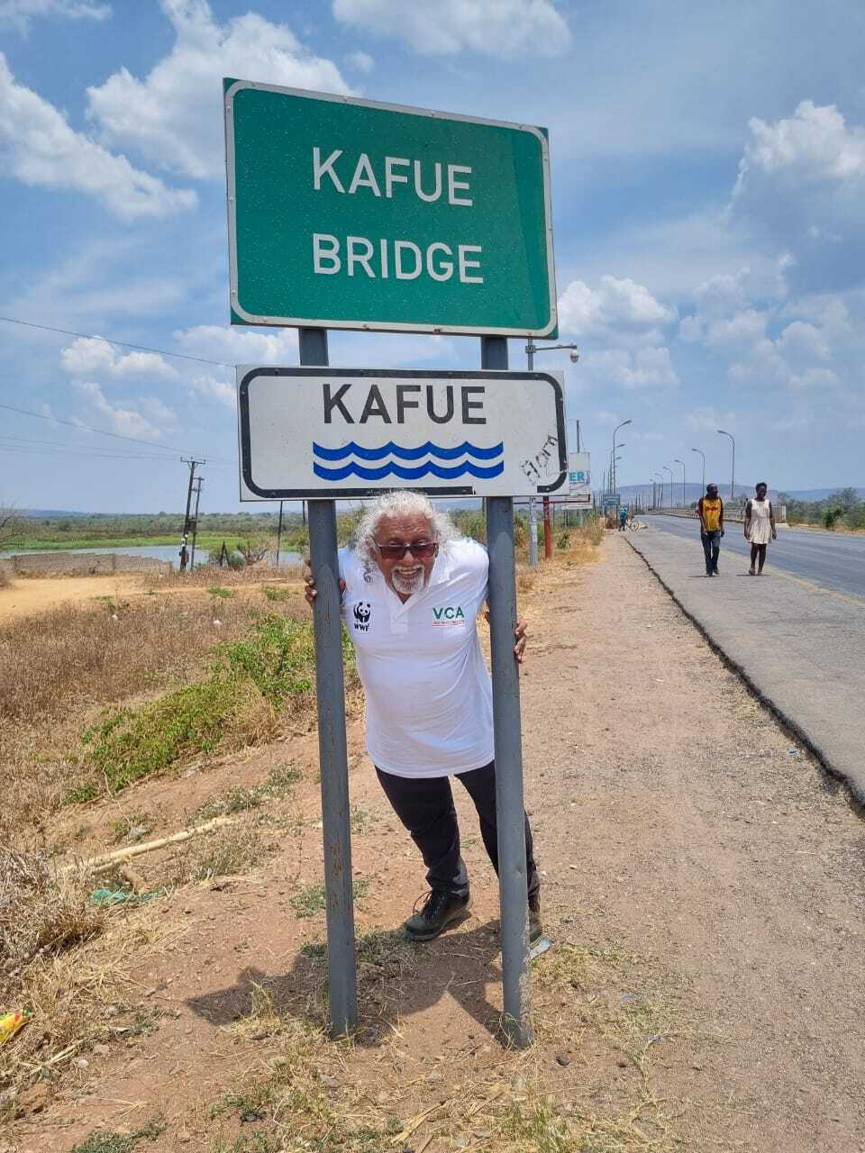 Man Standing under a sign for Kafue, Zambia