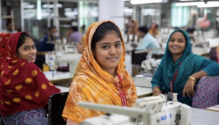 Three women working in a garment factory smiling at camera