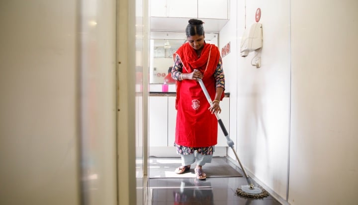 The Business of Care. Women from Bangladesh wearing red overall mops floor