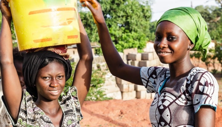 Two young women from Senegal transporting water