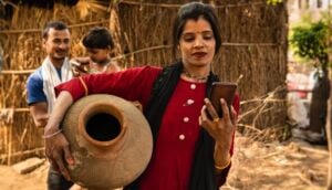 Digital Wage Payments Traditional rural indian woman carrying mud pot and using smartphone in village