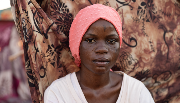 Nyauke, 18, sits at the UNHCR transit center near the Joda border point in Renk, South Sudan, after fleeing the conflict in Sudan. World Refugee Day 2024