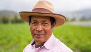 empowering the poor through business - Portrait of a Latin American farmer working in agriculture at a farm and looking at the camera smiling