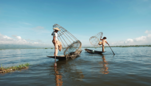 Two Fishermen riding a boat on body of water - Credibility for Equity and Livelihoods